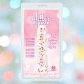 A packaged clear sex toy labeled "Glittergasm Dong - Red and Orange Swirl 7"" by Icon Brands, featuring colorful glitter inside, "body-safe" claims, and described as your glittery love toy on a pink, sparkly background.